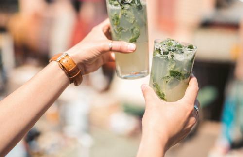 Two people holding up mojito drinks 