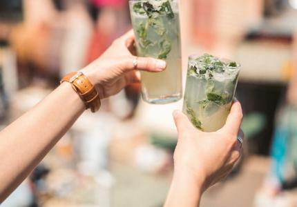 Two people holding up mojito drinks 