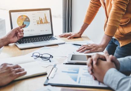 People reviewing financial report on laptop with graphs