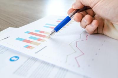 Person holding a pen over paper graphs 