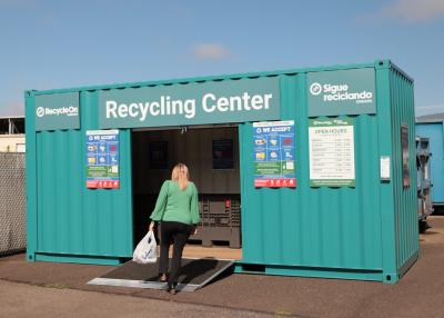 Woman carrying recyclable materials into metal RecyleOn center