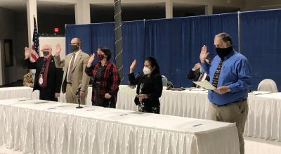 Five Council members with their right hand raised taking the Oath of Office
