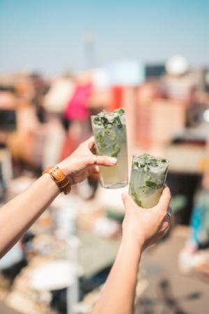 Two people holding up mojito drinks 