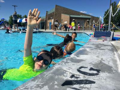 Children stretch arm in swimming pool for swim lessons