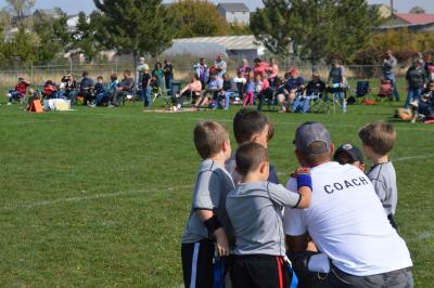 Photo of youth football players surrounding their coach.