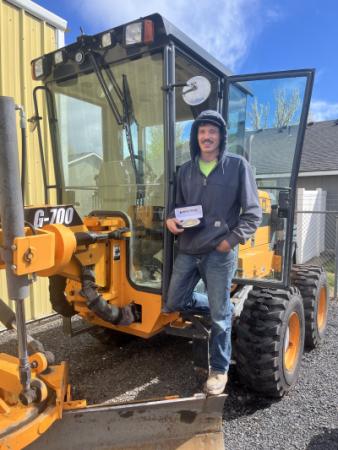 Jake Noyes displays a buckle tropy on a road grader