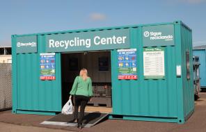 Woman carrying recyclable materials into metal RecyleOn center